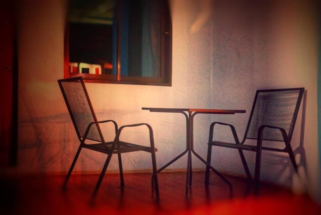 A small dining area with two chairs and a table, positioned near a window with a view of the outside.