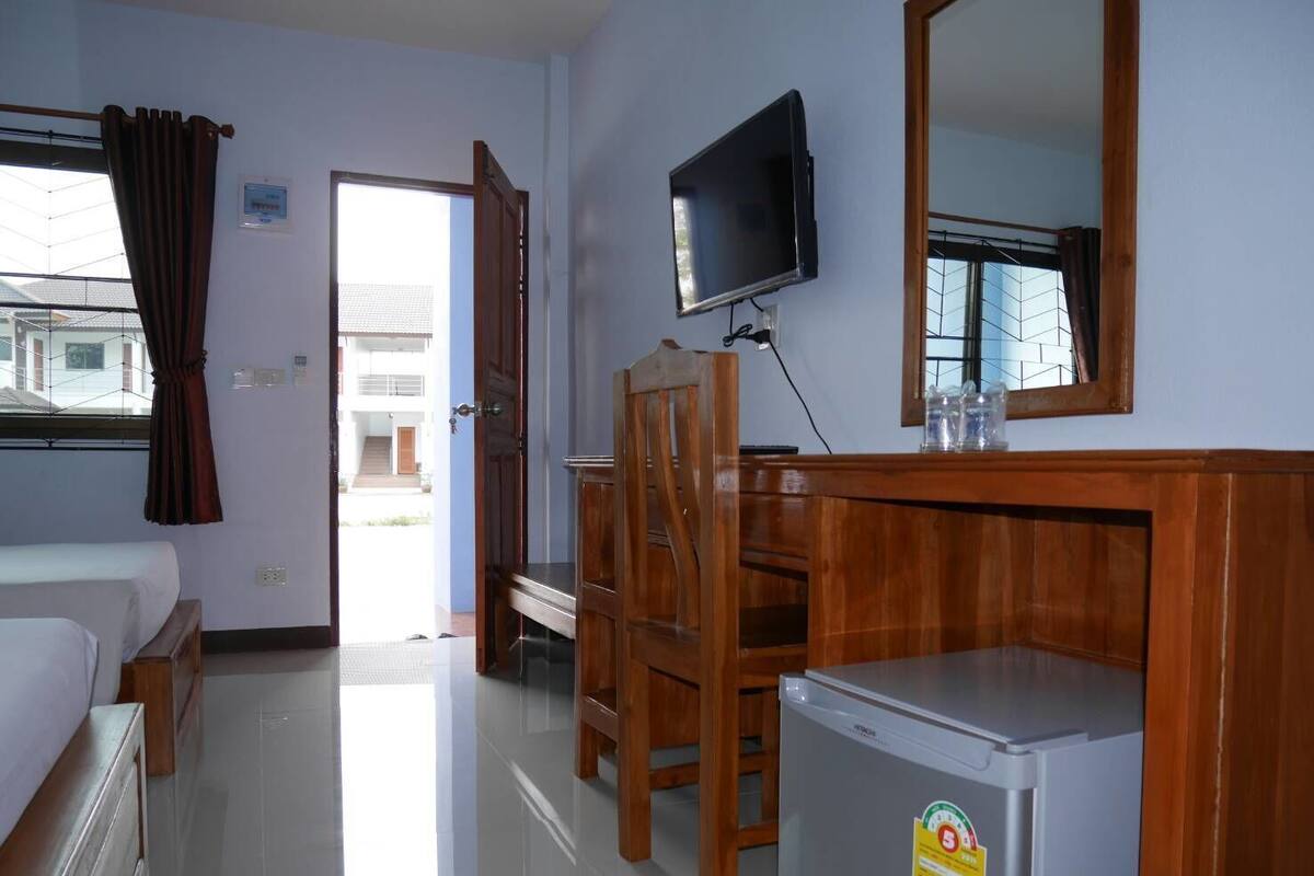 A hotel room with a bed, a desk, a chair, a television, and a refrigerator.