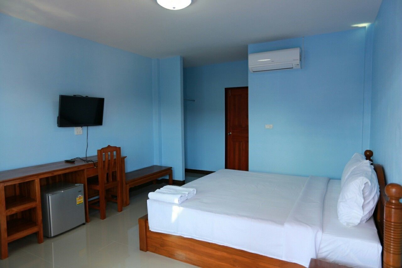 Una habitación de hotel con una cama, un escritorio con una silla, una televisión y un equipo de aire acondicionado.