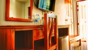 A wooden chair with a television mounted above it, a mirror, and a cabinet with bottles. - Tararin (Chiang Saen)