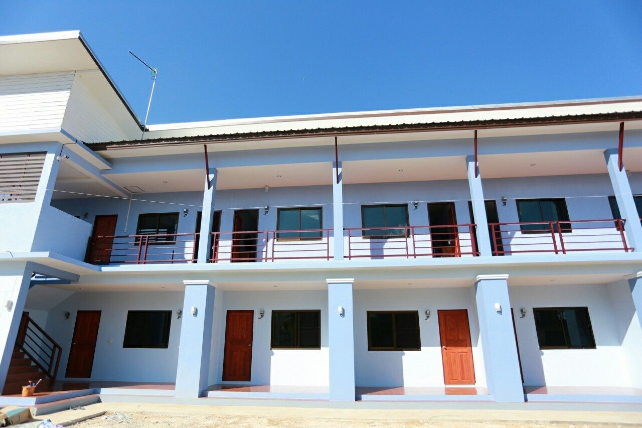 A two-story building with a flat roof, multiple balconies, and a series of windows.