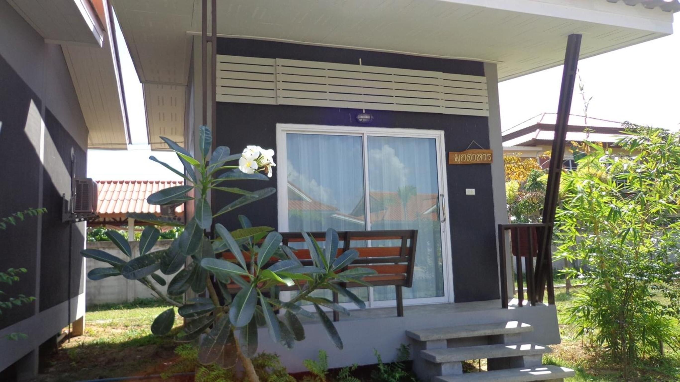 A building with a dark facade, a white door, and a bench outside.