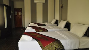 A hotel room with three beds, each with white linens and a red decorative blanket.