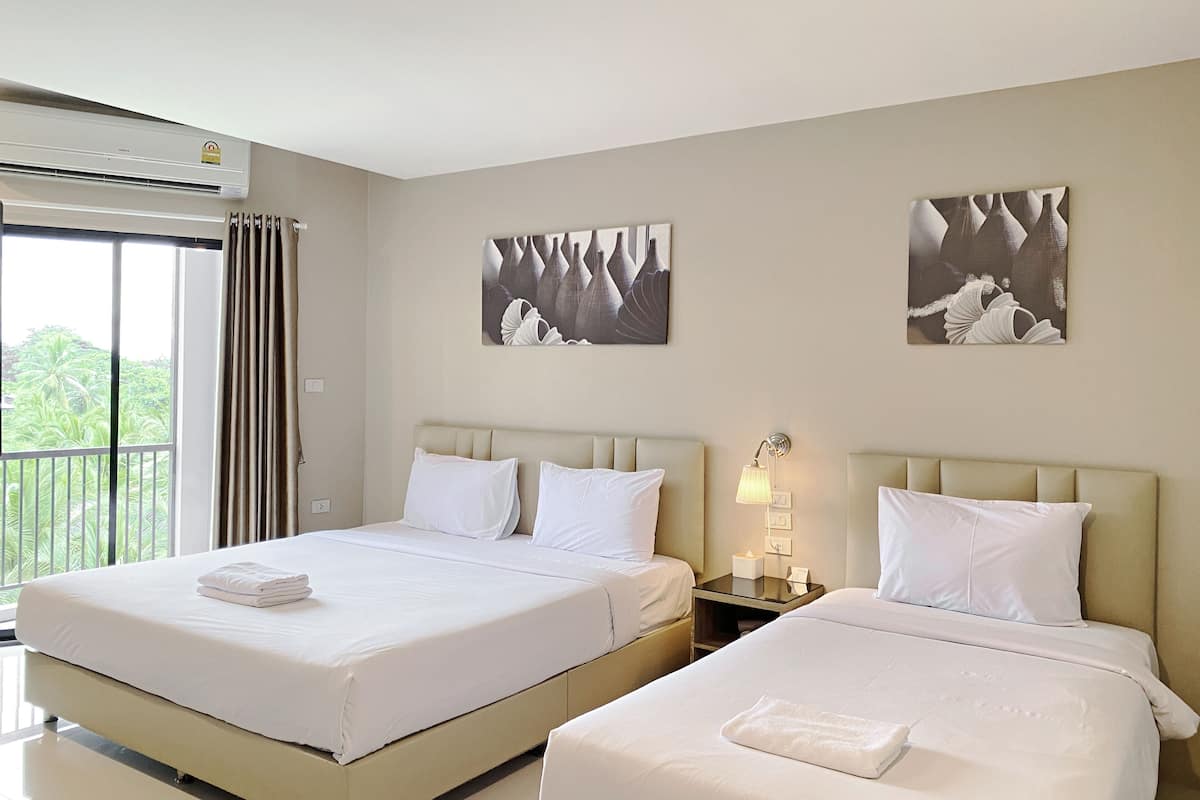 A hotel room with two beds, a balcony, and artwork on the walls.