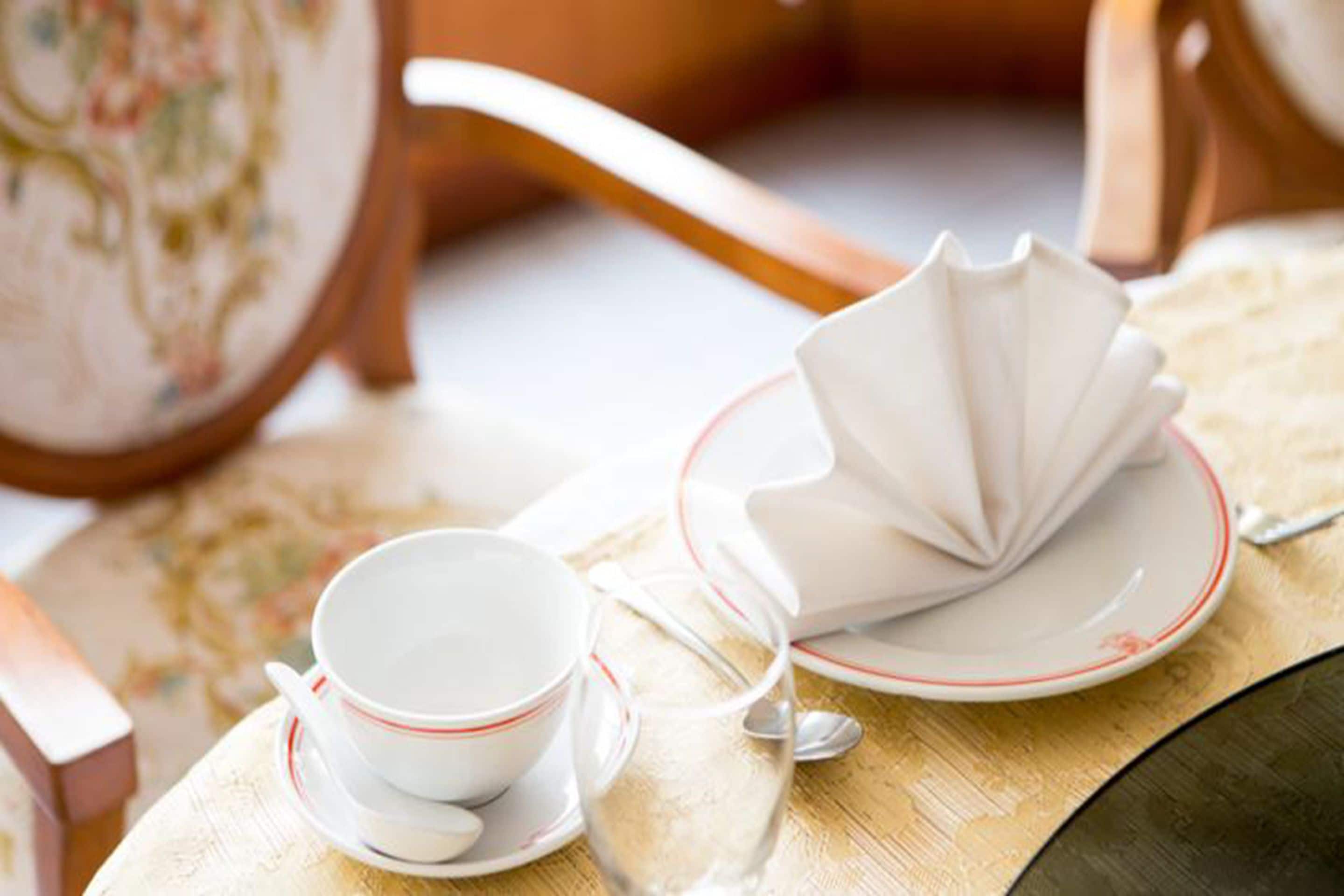 Un juego de té con taza, plato y una servilleta doblada sobre una mesa.