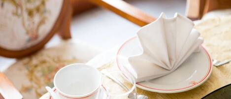 Un juego de té con taza, plato y una servilleta doblada sobre una mesa.