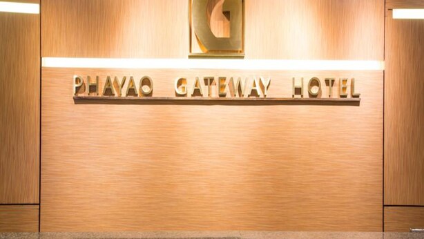 Un cartello in legno con la scritta "PHAYAO GATEWAY HOTEL" e un grande logo dorato a forma di 'G'.