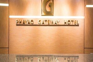 Een houten bord met de tekst 'PHAYAO GATEWAY HOTEL' en een groot gouden 'G'-logo erboven.