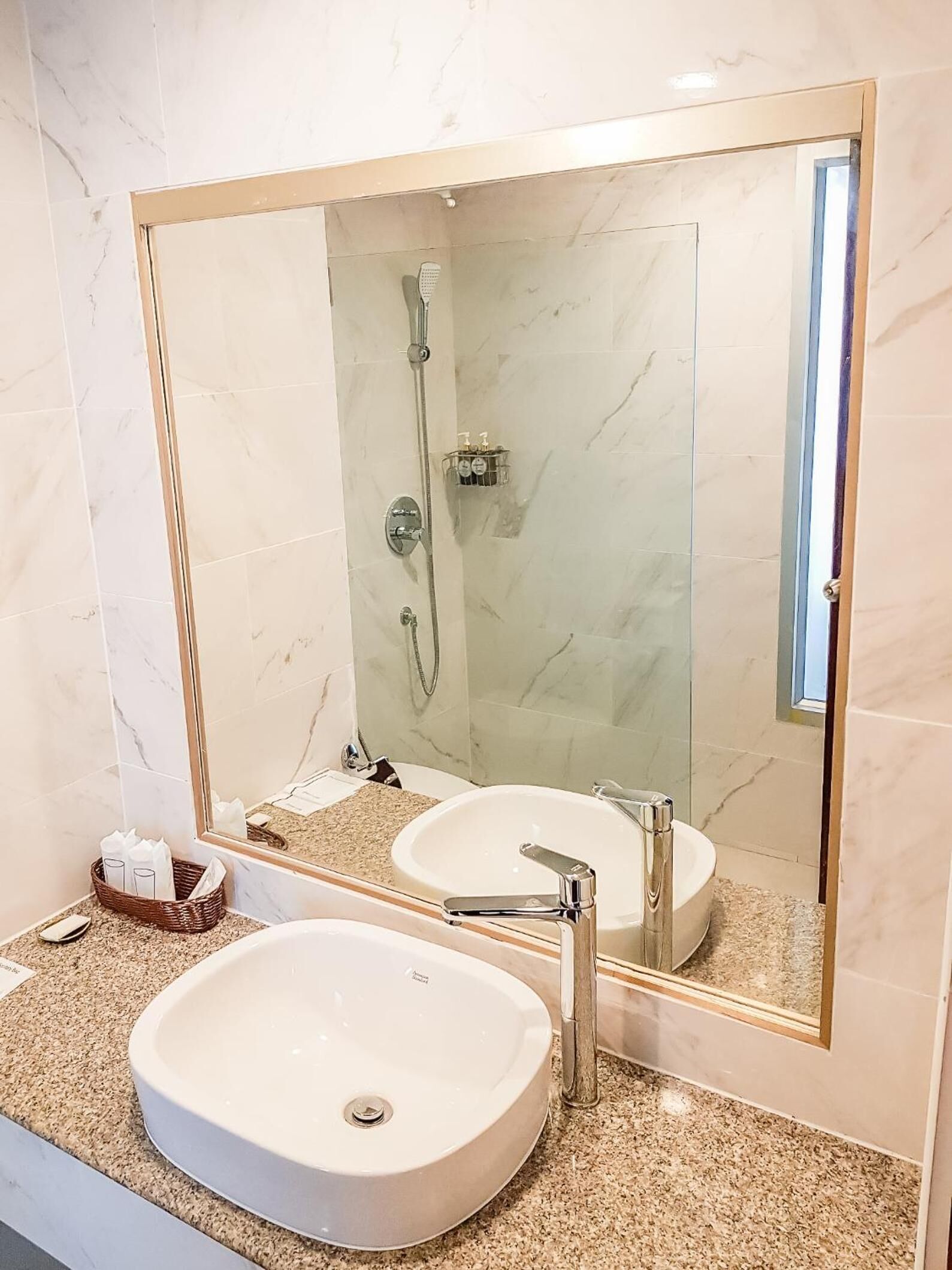 Un baño con un espejo grande, dos lavamanos, una ducha y un perchero para toallas.