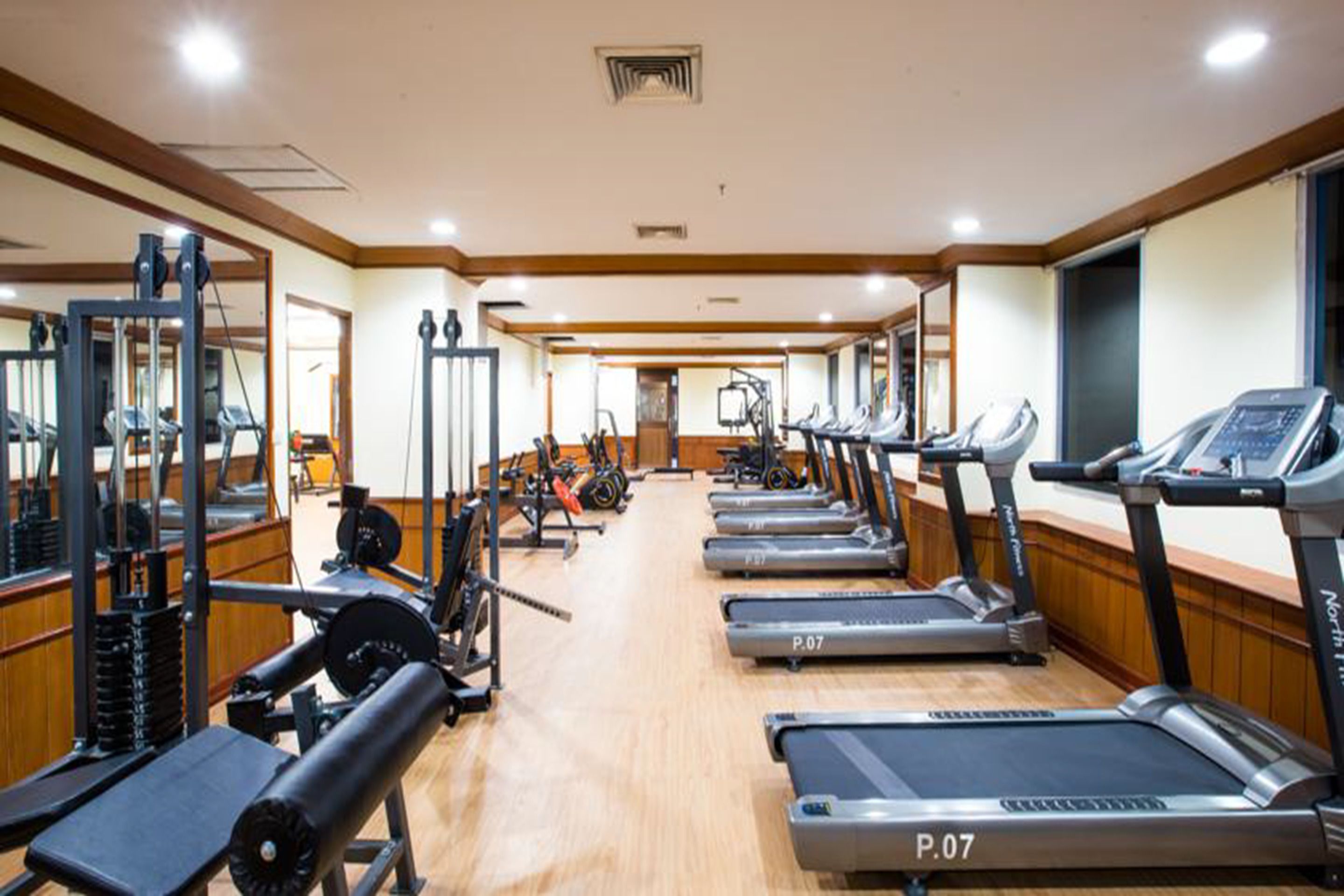 A gym with treadmills, weight machines, and mirrors.