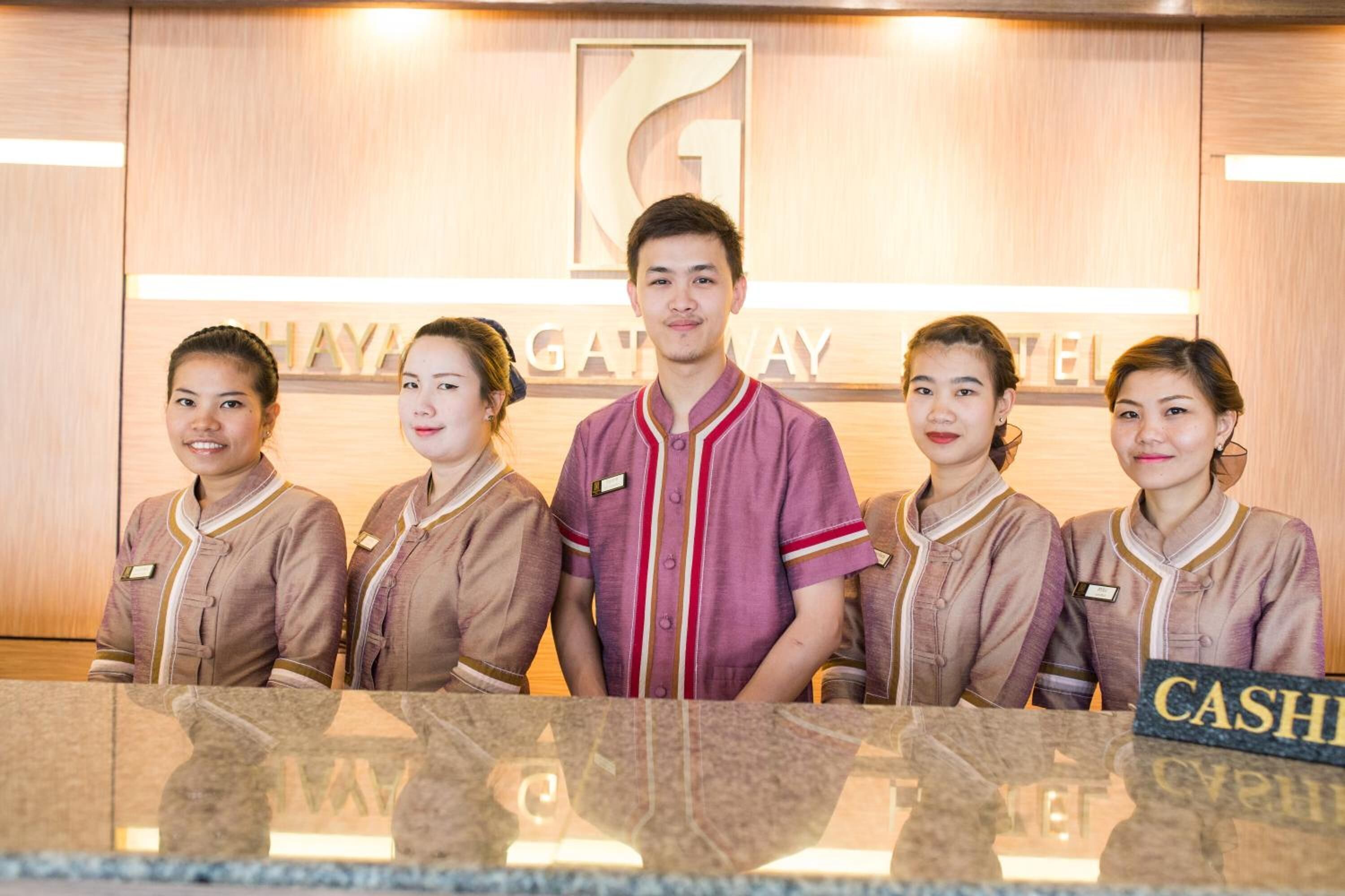 A reception area with a wooden backdrop and a sign that reads "GAYATHAY GATEWAY HOTEL".