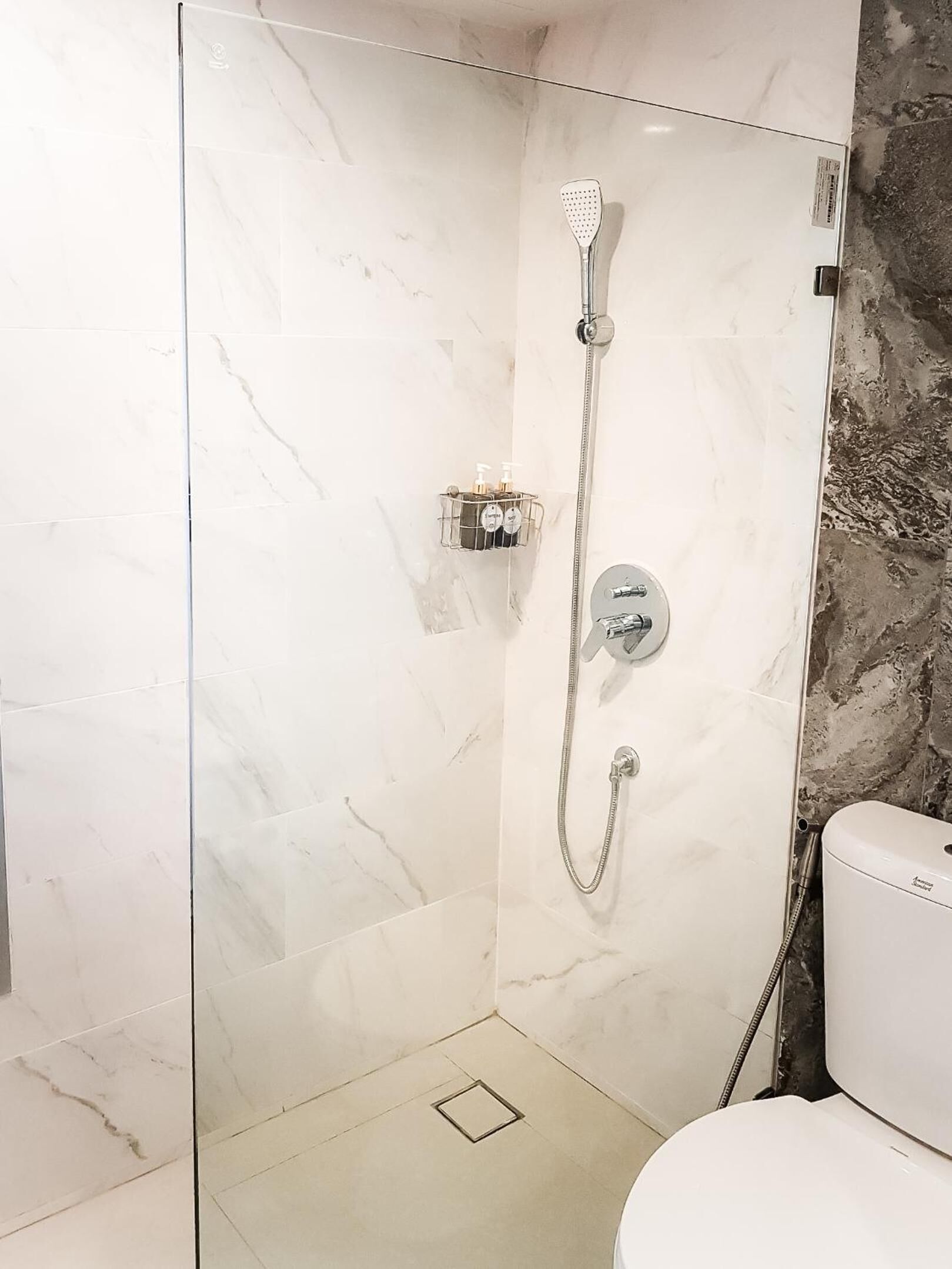 Ducha envuelta en vidrio con cabezal de ducha de mano y grifo empotrado.