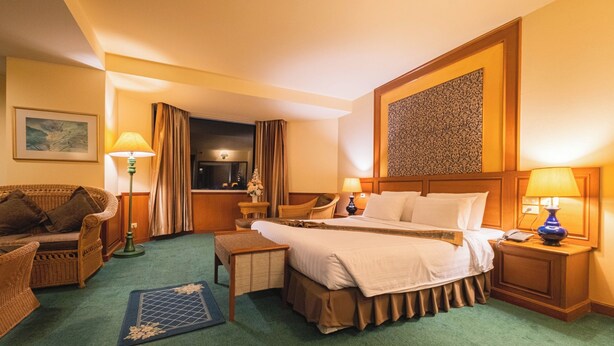 A hotel room with a bed, a sofa, a desk, and a chair.