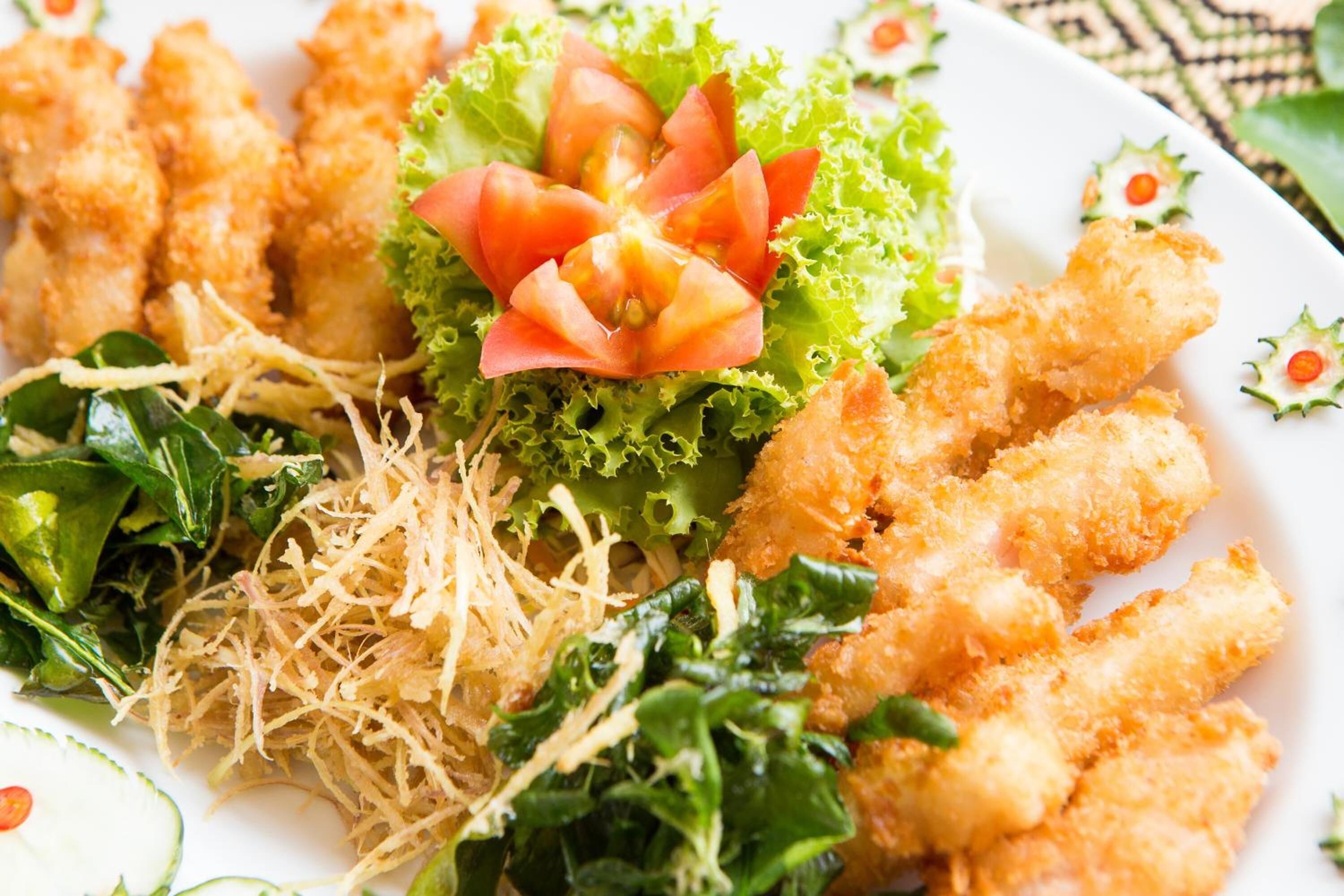 A plate of food with fried items, lettuce, and shredded vegetables.