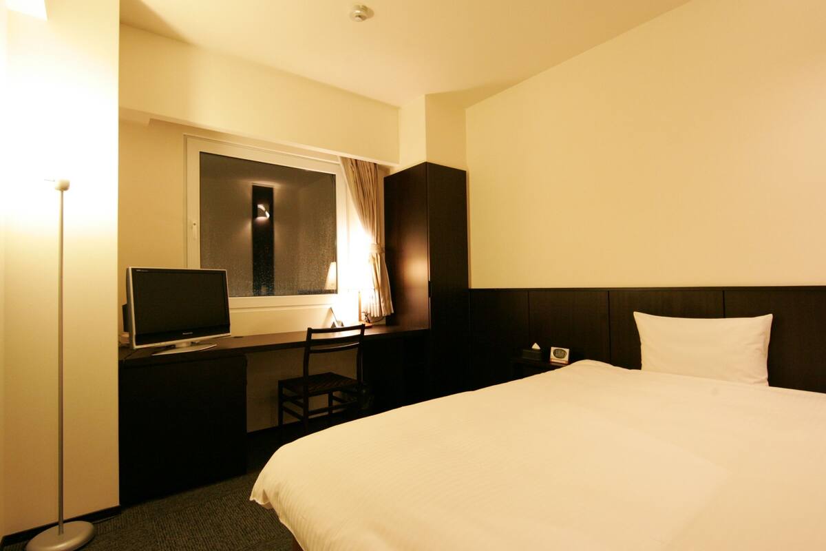 Une chambre d’hôtel avec un grand lit, une télévision, un bureau et une chaise.