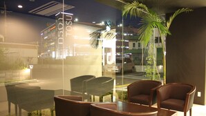 Un espace de détente intérieur moderne, doté d’une paroi vitrée donnant sur une rue.