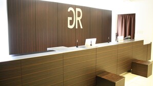 Un comptoir d’accueil avec un revêtement en bois et un grand logo « DR ».
