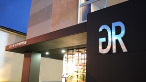 L’extérieur d’un hôtel, avec une enseigne bien visible indiquant « DR » et une autre, plus grande, au-dessus de l’entrée, indiquant « Green Rich Hotels ».