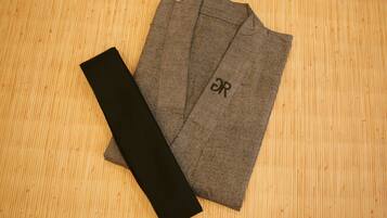 A grey suit jacket with a black tag on a wooden floor.
