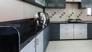 Una cocina moderna con encimeras negras, armarios blancos y salpicadero de azulejos.