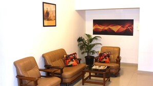 Una sala de estar con un sofá, dos sillones, una mesita de centro y una planta en maceta.