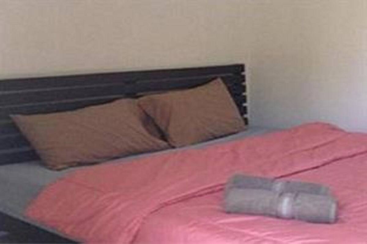 Un lit avec une couverture rose et deux oreillers marron.