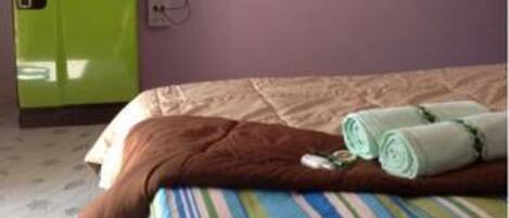 Una habitación de hotel con una cama, un minibár verde y un televisor montado en la pared.