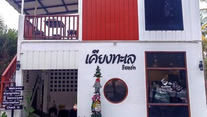 A two-story building with a red and white facade, a balcony, and a Christmas tree decoration.