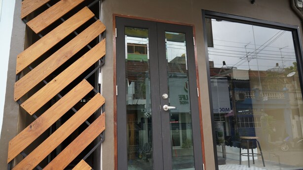 A modern building entrance with a glass door and a wooden slat design on the left. - Hive28 (Bangkok)