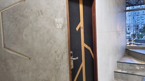 A hallway with a door labeled "HIVE 3/3" leading to a staircase with a checkered floor pattern. - Hive28 (Bangkok)