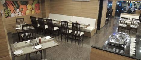 A restaurant with booths and tables, a buffet area, and a wall mural of fruits and vegetables.