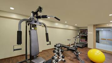 A gym with exercise equipment, a treadmill, and a large exercise ball.