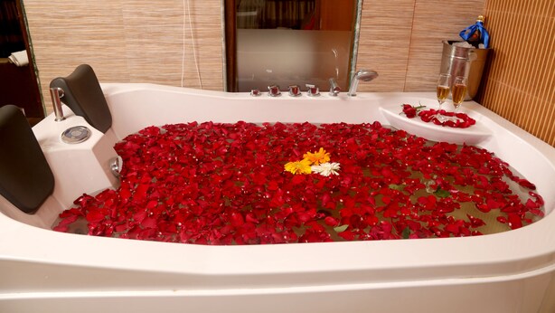 Uma banheira cheia de pétalas de rosa e taças de champanhe.