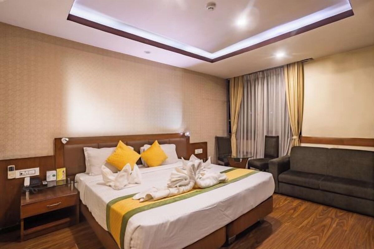 Una habitación de hotel con una cama bien hecha, un sofá, un escritorio con teléfono y televisión.