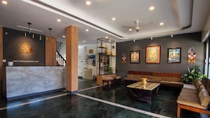 A hotel lobby with a reception desk, seating area, and artwork on the walls. - Hotel Ananda Inn (Lumbini)
