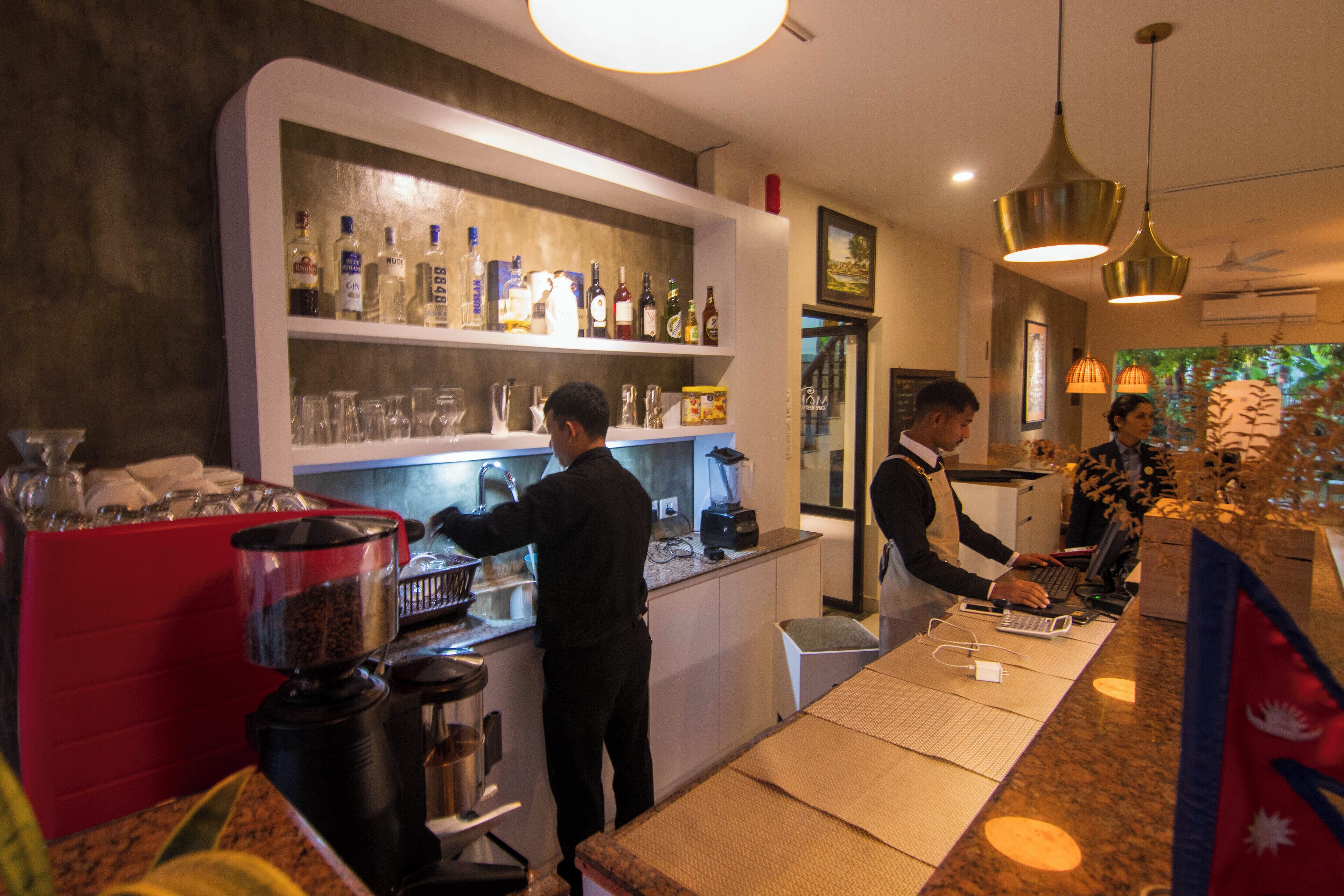 A bar area with a counter, shelves of bottles, and a coffee machine.