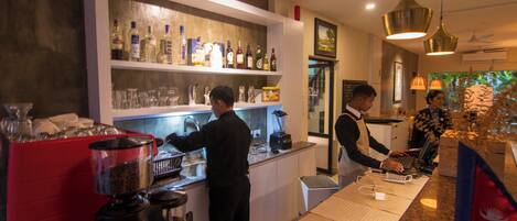 A bar area with a counter, shelves of bottles, and a coffee machine.