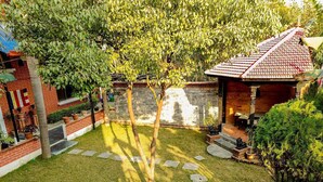 A well-maintained garden with a paved patio area, a brick wall, and a small gazebo. - Hotel Ananda Inn (Lumbini)
