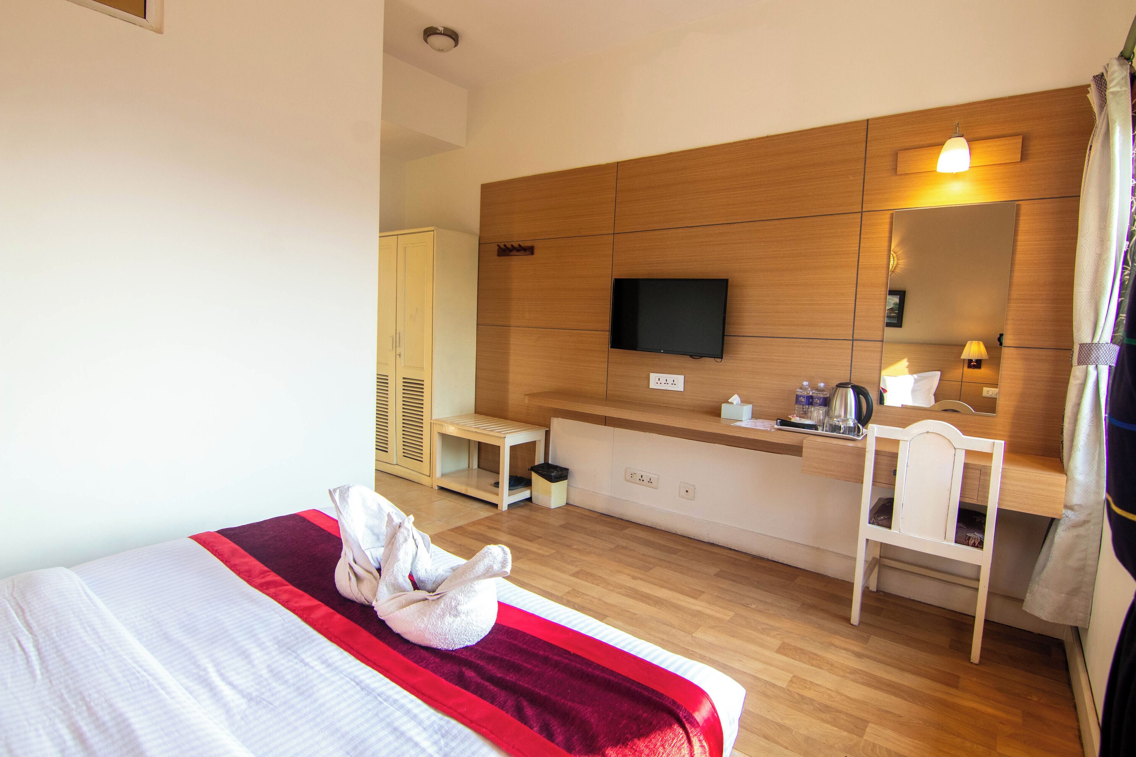 A hotel room with a bed, a desk, a television, and a mirror.