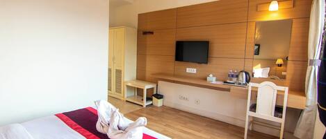 A hotel room with a bed, a desk, a television, and a mirror.