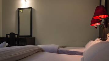 A hotel room with two beds, a mirror, a desk, and a red lamp.