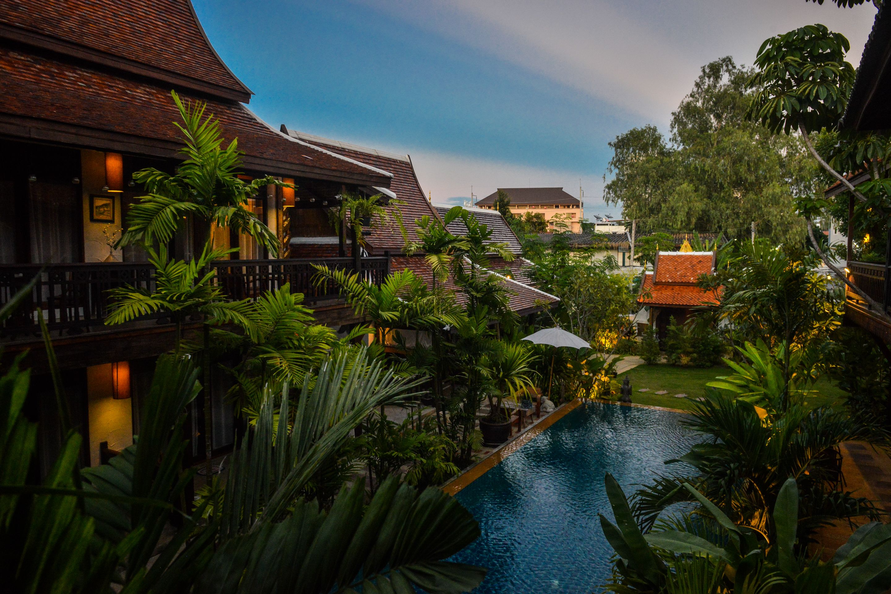 A traditional building with a swimming pool surrounded by lush greenery.