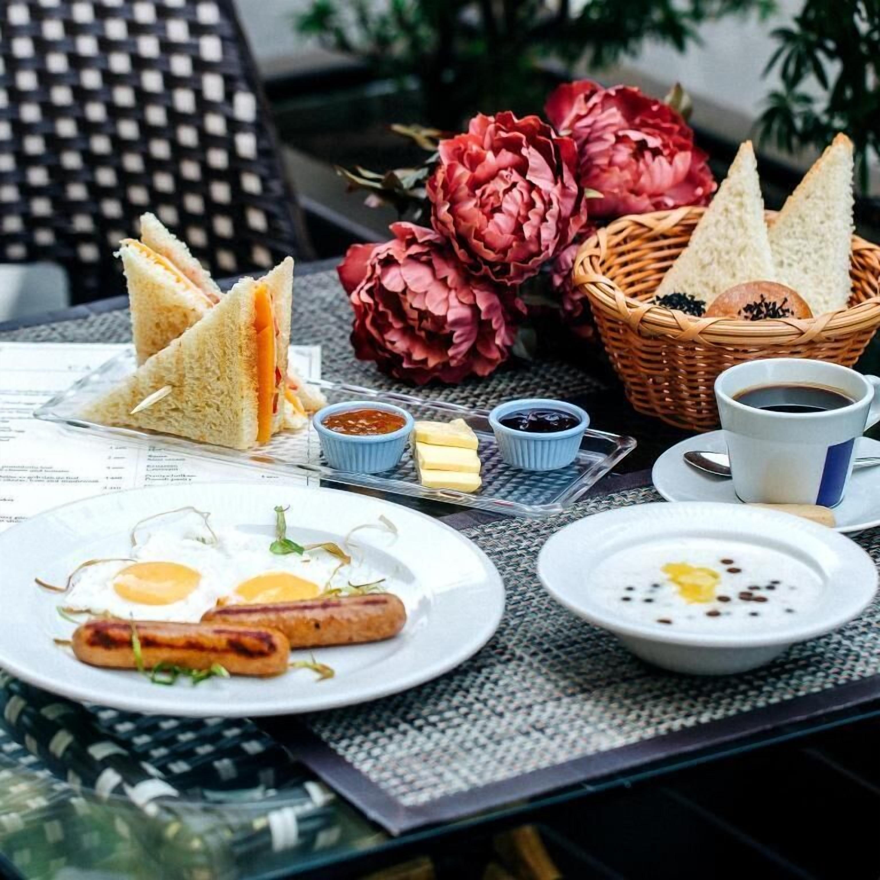 Een ontbijttafel met belegde broodjes, eieren, worstjes en koffie.