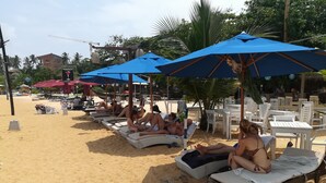 A beachside lounge area with sunbeds and umbrellas. - The Villa Hotel (Unawatuna)