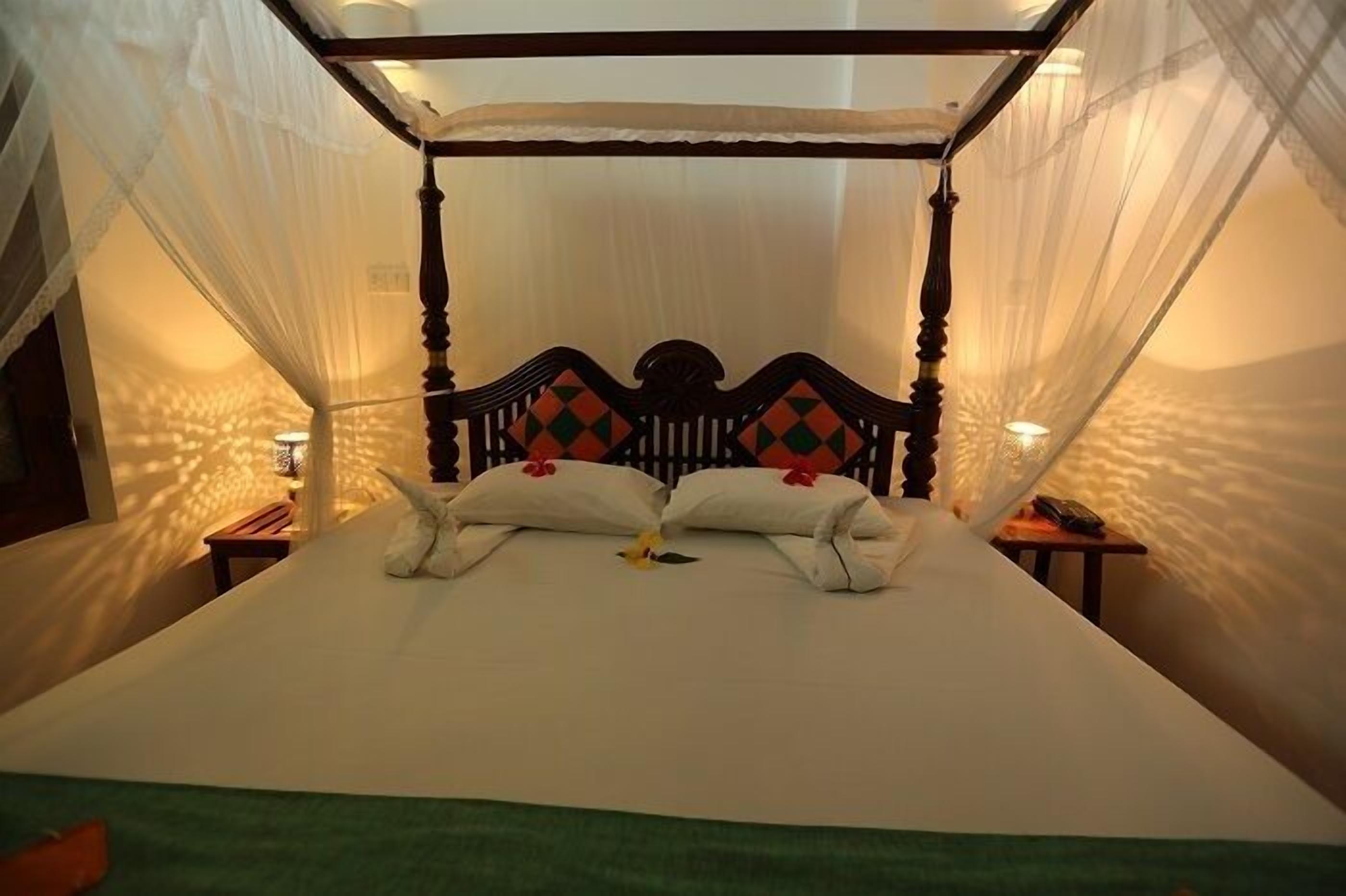 A bed with a canopy, pillows, and a bedside table.