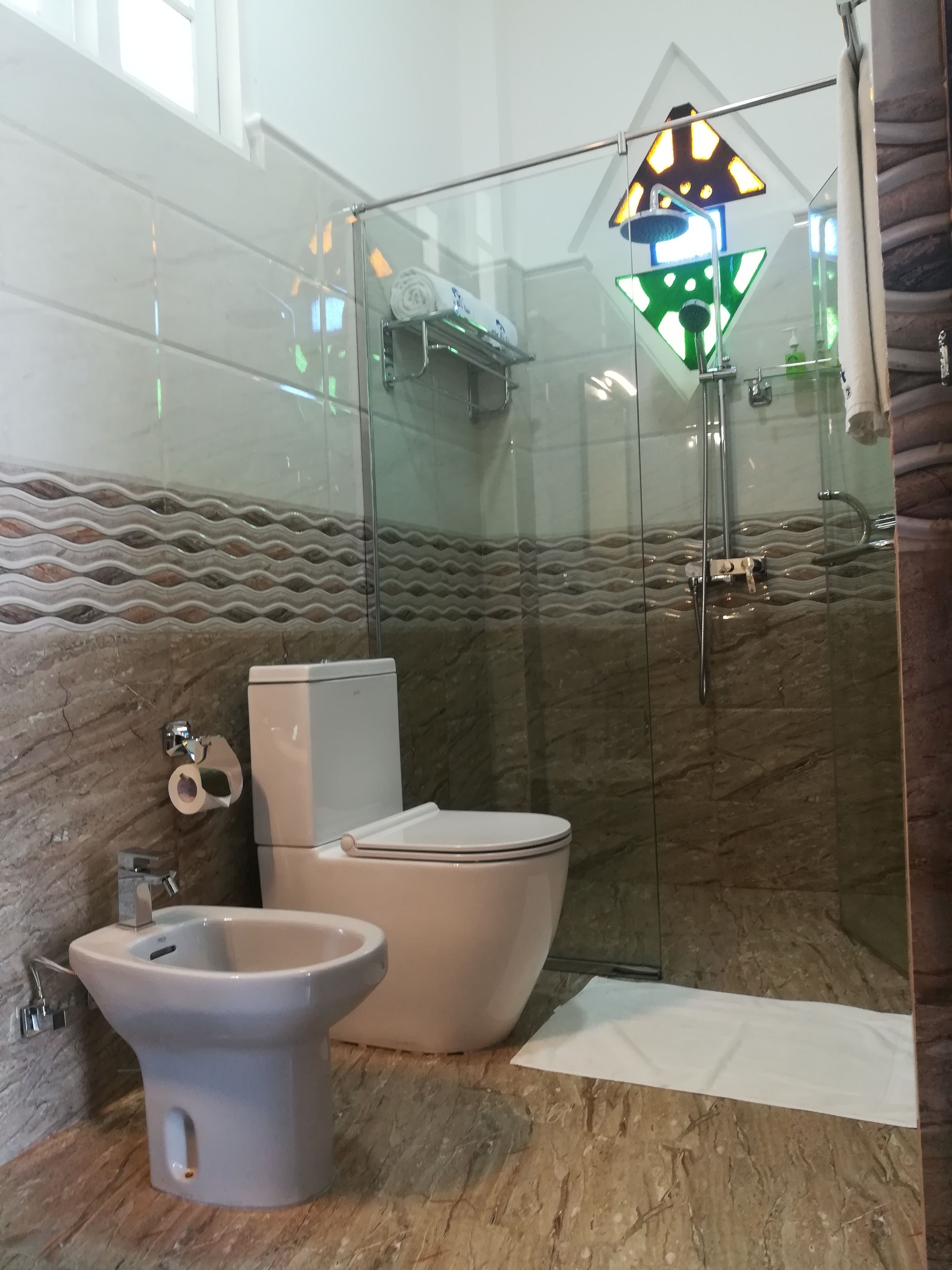 A bathroom with a glass-enclosed shower, a toilet, and a bidet.