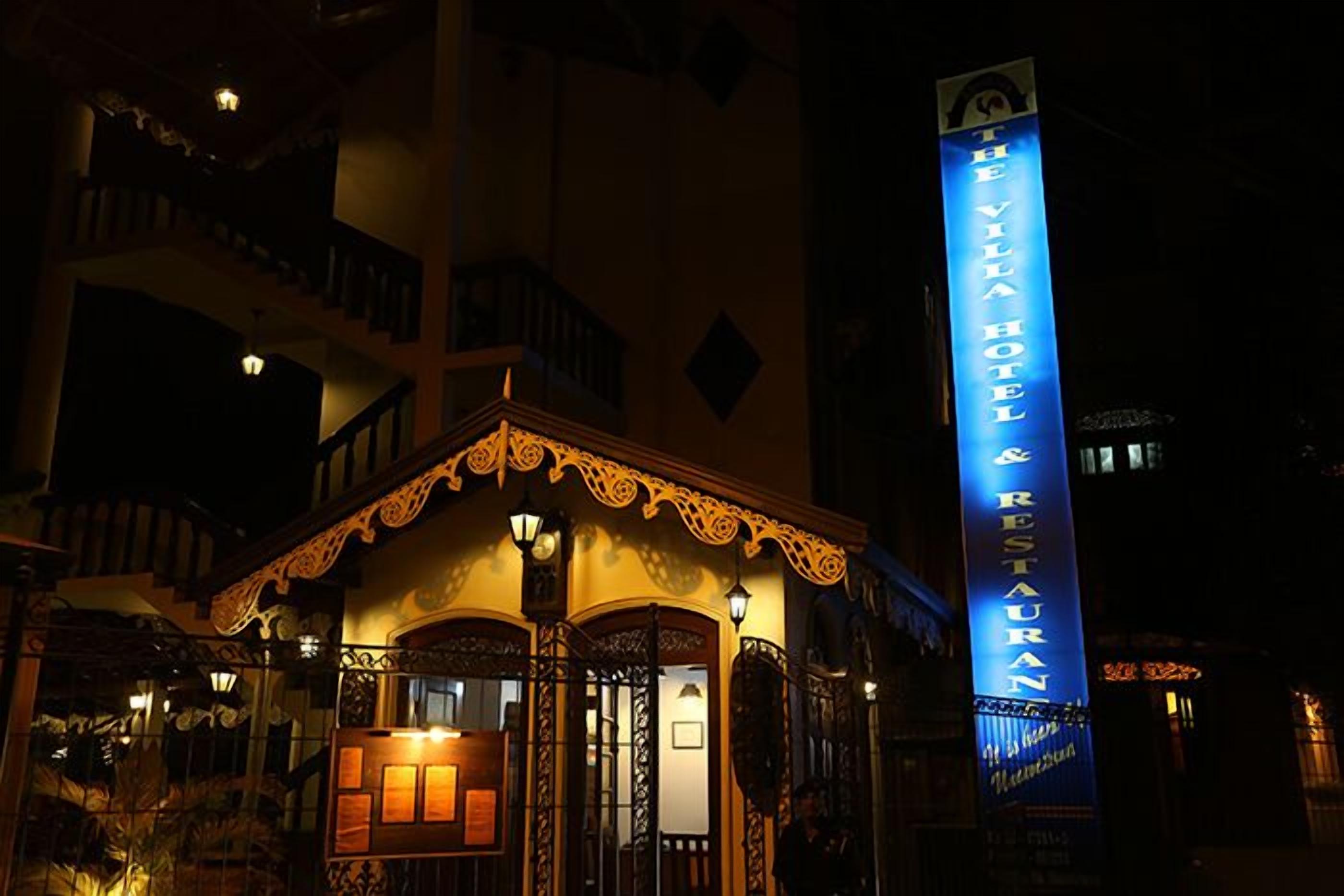 Un hotel con un cartello verticale ben visibile con la scritta “The Villa Hotel & Restaurant”.