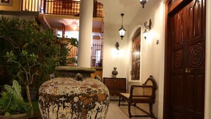 A spacious lobby with a large, rustic planter, a wooden bench, and a traditional wooden door. - The Villa Hotel (Unawatuna)