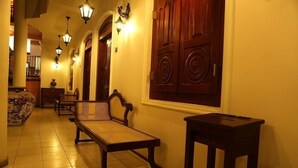 A hallway with a bench, a small table, and a wall-mounted lamp. - The Villa Hotel (Unawatuna)