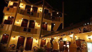 A multi-story building with balconies and warm lighting, featuring a central staircase and a bar area. - The Villa Hotel (Unawatuna)